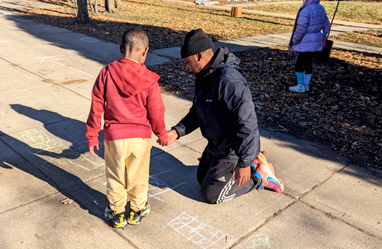 Adult and child draw with side walk calk at Pillsbury Elementary School