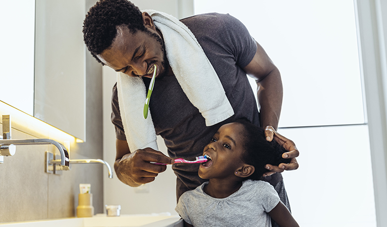man and child brushing their teeth